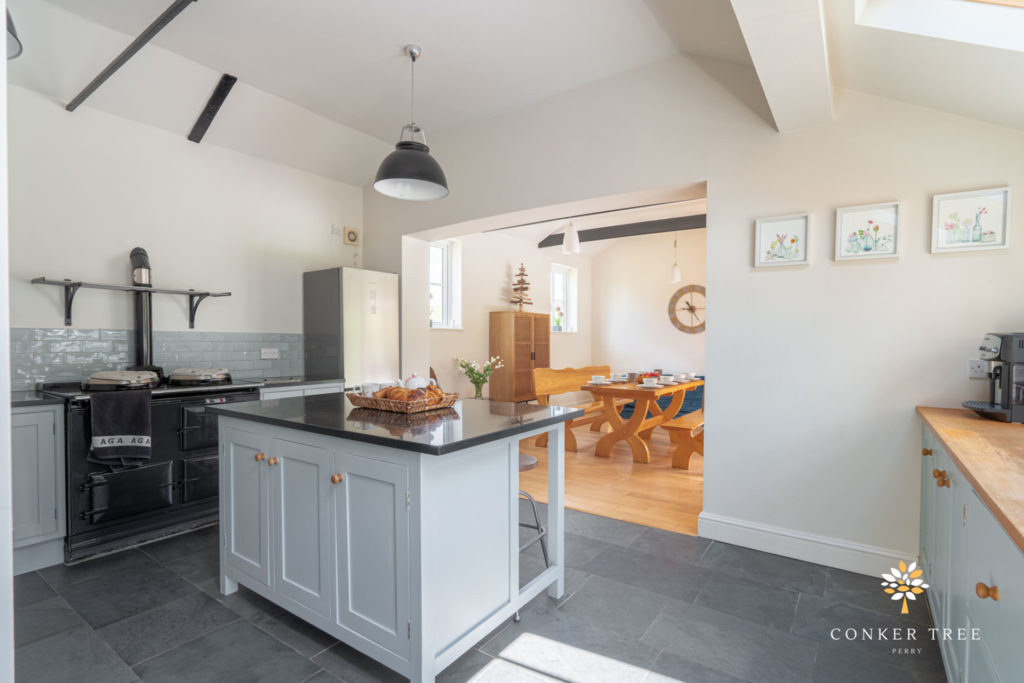 A grey farmhouse kitchen at our accommodation in Cambridgeshire, Conker Tree House, with grey kitchen island and black aga.