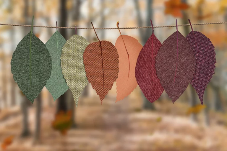 Eight felt leaves hang from a line ranging in colours from green to red, to purple.